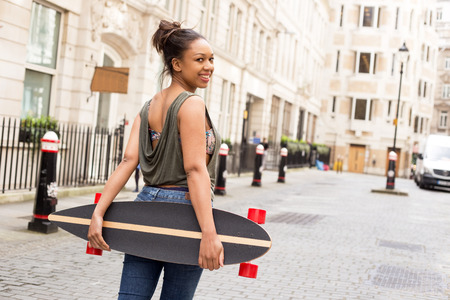 a young woman looking back holding a skateboardの写真素材