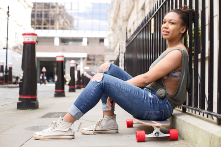 young woman in the street sitting on her skateboardの写真素材