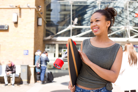 a happy young woman holding a skateboardの写真素材