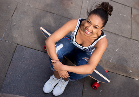 young womna sitting on her skateboardの写真素材