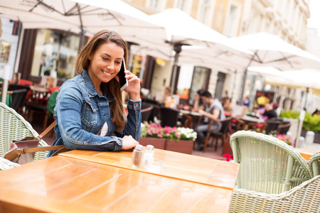 young woman talking on the phone at a restaurantの写真素材