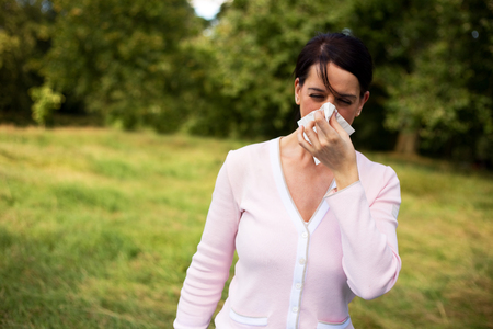 young woman suffering from a cold blowing her noseの写真素材