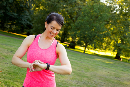 young woman checking her fitness monitor in the parkの写真素材