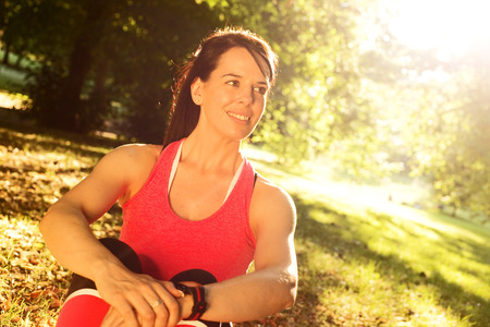 young woman sitting in the park after exerciseの写真素材