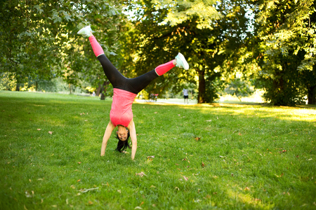 girl performing cartwheel in the parkの写真素材