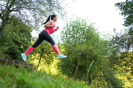 fitness girl out for a run jumping over a logの写真素材
