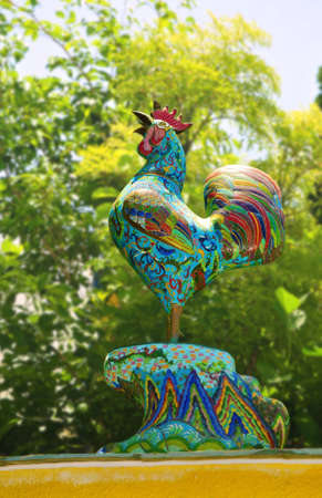 Ceramic Rooster in front of green leaf backgroundの写真素材
