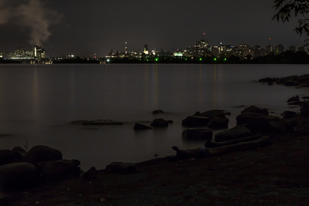 City lights from downtown Ottawa and Parliament Hill reflect over the Ottawa River at night.の写真素材