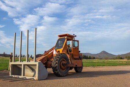 Orange farming tractor with gray plow on a sunny clear day.
