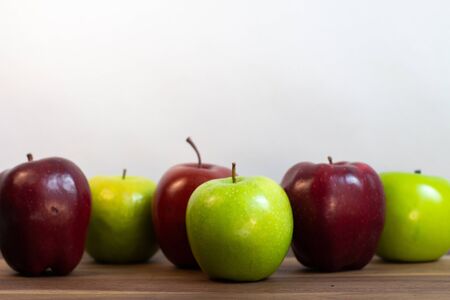 Group of red and green apples on a table with a white backgroundの写真素材