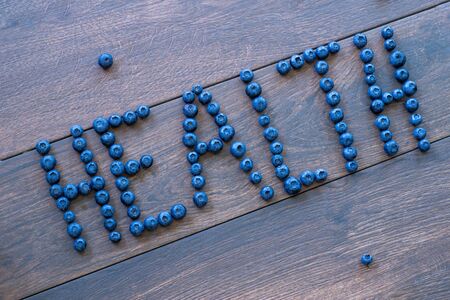 Blueberries on a wooden table spelling out the word HEALTH. Healthy snackの写真素材