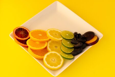 White plate of rainbow fruits representing LGBT on a yellow background.