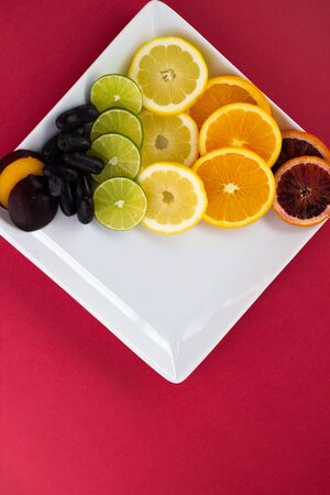 Rainbow of fruits on a white plate against a red background. LGBTの写真素材