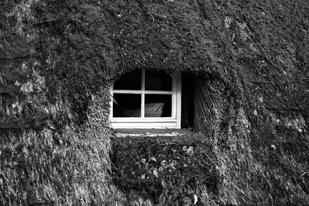 A window in the roof of a thatched roof houseの写真素材