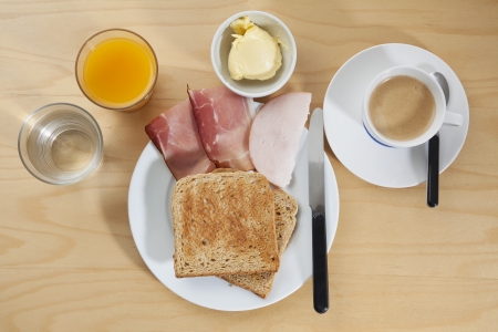 Simple breakfast concept with toast on a plate, knife and a glass of orange juice, water and coffee.の写真素材