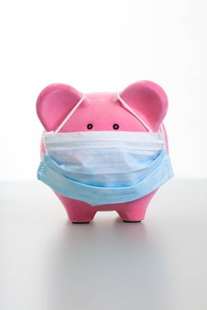 Pink piggy bank wearing a protective face mask  Concept for protection, flu, virus, sickness の写真素材