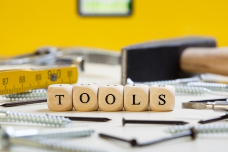 Concept of dices with letters forming words: Tools. Surroundings and background of hammer, screws, nails and other tools.

Dices made from wood with natural imperfections.の写真素材