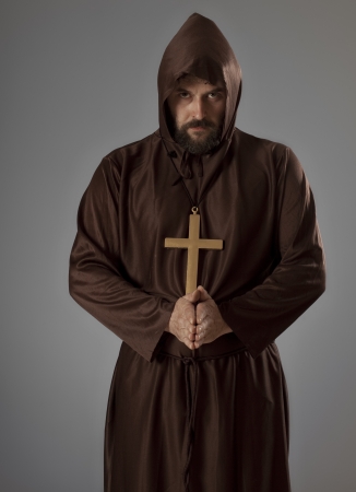 Studio shot of a man wearing a monk robe, holding his hands in praying pose while looking at camera.の写真素材