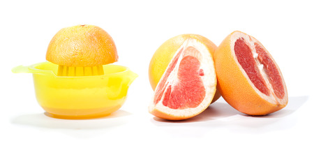 Whole grapefruit in back, pieces cut apart in front, another piece on a press to make healthy juice....