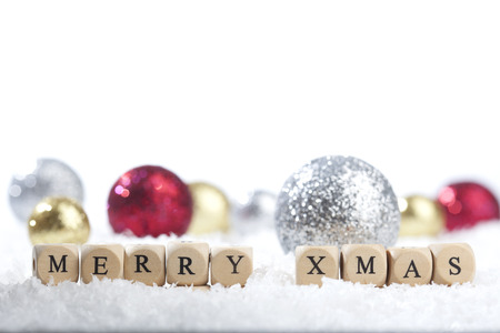 Merry Xmas text in front of golden Christmas decoration balls on a (artificial) snow ground.の写真素材