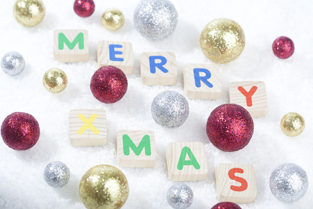 Merry Xmas text in front of golden Christmas decoration balls on a (artificial) snow ground.の写真素材