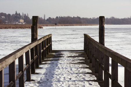 Wooden quay for river boats, covered in snow on frozen river in winter.

River Havel, Brandenburg, Germany.の写真素材