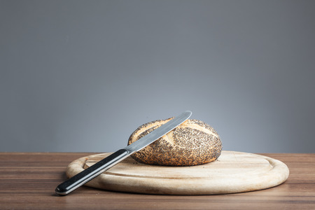 Breakfast plate with knife and poppy seeds bread roll の写真素材