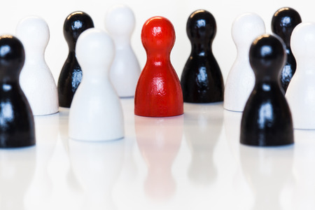 Single red toy figurine in a group of black and white.の写真素材