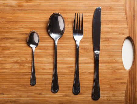 Kitchen or dinner knife, fork, spoons, cutlery made from stainless steel, studio shot on a wooden board.の写真素材