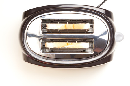 Black toaster with two slices of bread inside toasting. Studio shot, isolated on white background.の写真素材