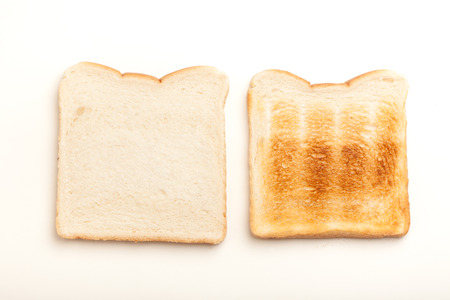 Two slices of bread, one raw, another toasted perfect. Studio shot on white background.の写真素材