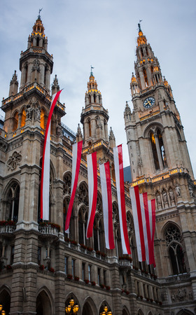 Beleuchtetes Rathaus in Wien mit Landesflagge und Blumenschmuck in Neogotik von Friedrich von Schmidt, Ãsterreich.のeditorial素材