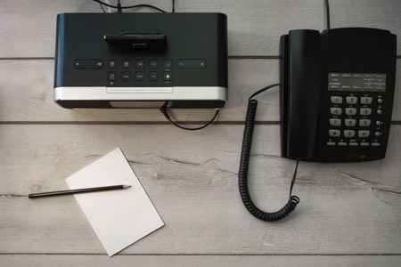 Standard Hotelzimmer Ausstattung mit Radiowecker, Tastentelefon und Notizblock auf Holztisch.の写真素材