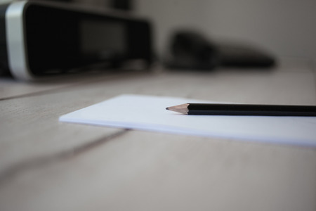 Bleistift auf leerem Notizblock, Holztisch in Hotelzimmer mit Wecker und Telefon im Hintergrund.の写真素材