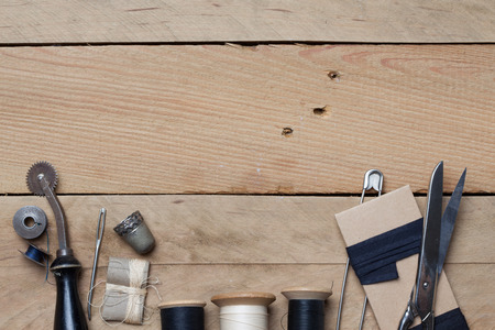 Set of tools with cutter, scissors, needle, thread spools for home made embroidery, needlework and tailoring, on wooden background.の写真素材
