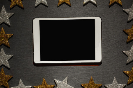 Table computer on slate background with frame of golden and silver stars, Christmas decoration.の写真素材