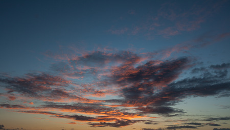 Background of red, purple, orange sky and clouds lit by the setting sun on a blue sky.