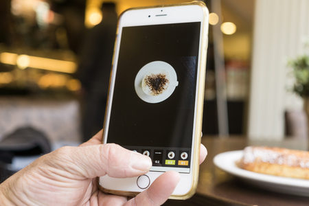 Berlin, Germany - May 17, 2016: Man editing his mobile photo of a coffee cup with iPhone and VSCO Cam app.のeditorial素材