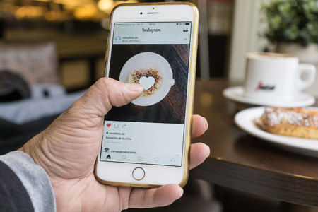 Berlin, Germany - May 17, 2016: Man using the newly designed Instagram app on his iPhone 6 Plus.