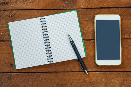 Note pad with pencil, smart phone on wood table, high angle viewの写真素材