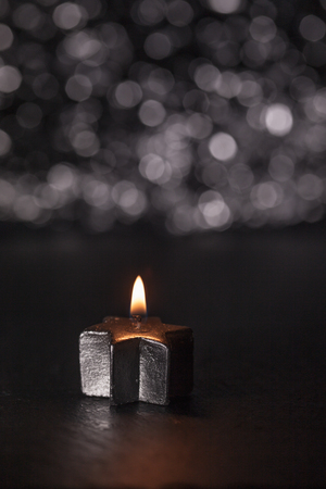 Lit silver candle on black background, bokeh lights and shallow depth of field, vertical image.の写真素材