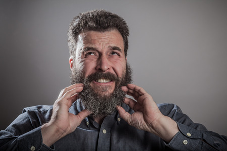 Scracthing face with both hands, Huge beard portrait, mature adult Caucasian manの写真素材