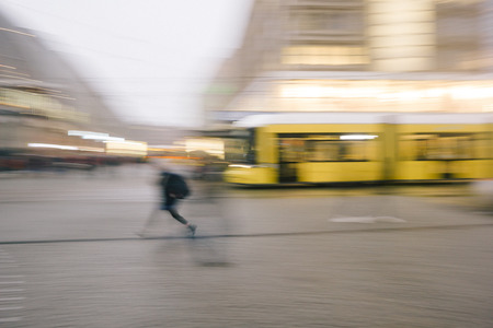 Person running in front of tram, cable car, intentional motion blur for anonymity, concept image of public transport, traffic.の写真素材