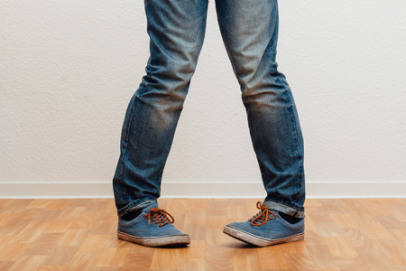 Bottom half closeup to man standing with knock-knees, people indoors studio shot.の写真素材