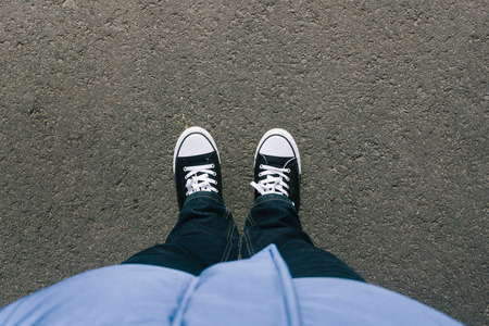 Pair of legs and shoes on asphalt ground, high angle footsie or flortrait, personal pespective from above.の写真素材