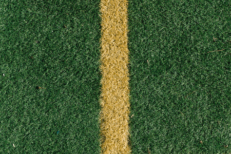 Yellow center line on football field, marking on artificial green grassの写真素材