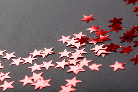 Decorative stars in red color on black background, closeup holiday season detail, shallow depth of field with selective focus.の写真素材