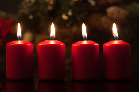 Advent candles in red, set of four to be lit on the Sundays leading up towards Christmas. Shallow depth of field with blurry background.の写真素材