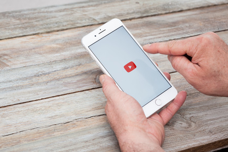 BERLIN, GERMANY - NOVEMBER 26, 2017: Man opening Youtube app on iPhone 7 Plus at a deskのeditorial素材