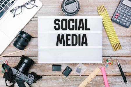 Social Media written in Light box on photography desk with camera, batteies, flash card items, grunge office deskt flat lay shot from aboveの写真素材